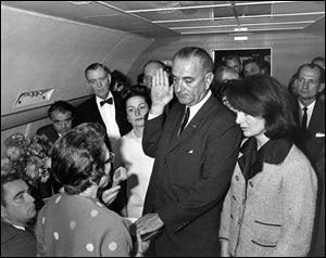 Lyndon B. Johnson is sworn in as president as Jacqueline Kennedy stands at his side in the cabin of the presidential plane on the ground at Love Field in Dallas. Judge Sarah Hughes, a Kennedy appointee to the federal court, left, administered the oath.
