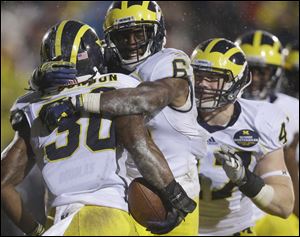 Michigan safety Thomas Gordon (30) celebrates with defensive back Raymon Taylor (6) after Gordon intercepted a pass in the third overtime, Saturday.