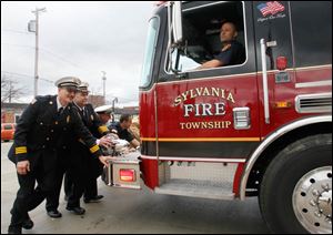 Maintaining a firefighter tradition, a truck is pushed into Fire Station 1 in Sylvania to mark its opening. From left: Sylvania Township Deputy Chief Mike Froelich, Chief Jeff Kowalski, Deputy Chief Mike Ramm, and firefighter Todd Walters. Driving is firefighter Mike Sobb.