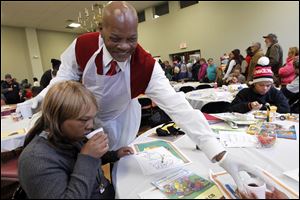 Volunteer Brian Jackson, right, serves drinks to a table of diners including Christina Lofton, left, from Toledo, during the 12th annual homeless holiday luncheon.