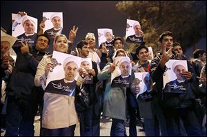 Iranians hold posters of President Hassan Rouhani as they cheer returning Iranian nuclear negotiators upon their arrival from Geneva in Tehran.  Iran insists its nuclear program is peaceful.