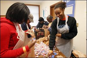 Volunters Deja Walker, left, and Victoria Turnbough assemble take-home bags for attendees during a holiday dinner for the homeless last week.