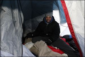 Bryan Davis sits inside his tent which he erected last week outside Best Buy.