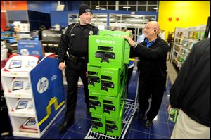 DeKalb police Officer Q.S. Starnes, left, helps Best Buy manager Sammy Abuata wheel in a pallet of Xbox One game sets for a door-buster sale just before midnight on Thanksgiving Day in Dunwoody, Ga. All of the store's 120 employees were on hand to ring up items after the electronics retailer opened on Thanksgiving this year. 