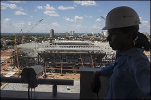 A worker stands next to a camera used to monitor the construction of the Arena Pantanal stadium that will host games during the 2014 World Cup soccer tournament in Cuiaba, Brazil.