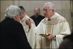 The Most Rev. Leonard P. Blair gives Communion during his final public Mass at Rosary Cathedral.