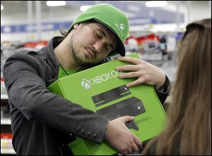 Emanuel Jumatate, from Chicago, hugs his new Xbox One after he purchased it at a Best Buy in Evanston, Ill.
