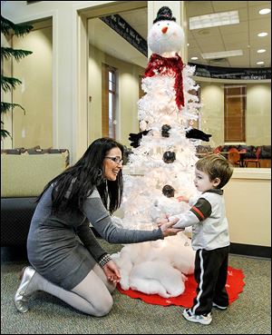 Shelley Skiver shows her grandson Collin Clark one of the decorated Christmas trees inside the Bedford Branch Library in Temperance. Seventeen trees with different themes are on display.