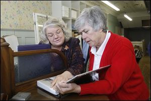 Kathleen Fix, left, and Julie Miller look at photographs and postcards of Fayette that date from the late 1800s to the present. The Normal Project, a patchwork of initiatives and programs, aims to develop what an organizer describes as Fayette’s social capital.