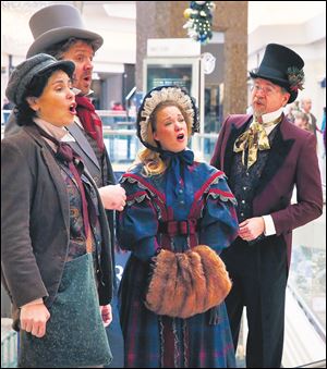 Members of the Original Dickens Carolers, right to left, Todd Felts, Kelly Watt, Brian Merz-Hutchinson, and Michelle Robison, sing holiday songs inside Cherry Creek Mall, in Denver.