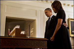 President Barack Obama and first lady Michelle Obama take a moment of silence in honor of the Newtown shooting victims on the one year anniversary of the tragedy, Saturday in the Map Room of the White House in Washington.