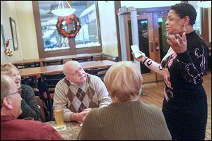 Toni Battle, a health-care navigator with the Neighborhood Health Association, speaks with Port Clinton residents Scott Jones, left, Judy Allen, Bob Allen, and Terri Jones at Our Brothers Place in downtown Toledo during a recent forum. A public sign-up will be held from noon to 7 p.m. Monday at the downtown library.