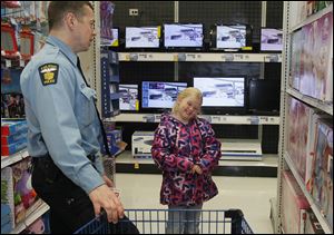 Toledo Police Officer Dan Henderson and Angel Grant, 7, evaluate an item in a toy department. Officers took 53 children shopping for the 12th annual Kids of Christmas program. They met at the Huntington Center downtown and then went to the Meijer store on Alexis Road to shop. 