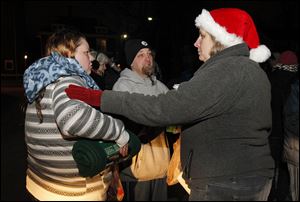 Julie and Keith Thompson are greeted by Toni Harms, right, after receiving food, a blanket, and scarves in the parking lot of Helping Hands of St. Louis. St. John’s and St. Ursula students meet every Monday to pass out food to the needy as part of the Labre program.