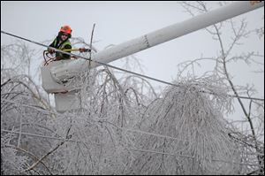 Andrew Powers, an arborist with Asplundh Tree Experts, clears iced branches from power lines along Mayflower Heights Drive in Waterville, Maine, on Monday.
