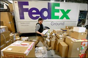 Package handler Chris Addison arranges boxes before load-ing a truck at a FedEx sorting facility in Kansas City, Mo. FedEx plans some deliveries in the Toledo area today.