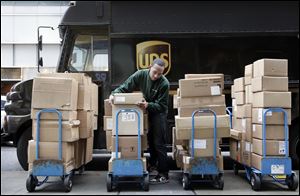 A UPS driver unloads packages from a truck and arranges them for delivery in New York. The company said today that the volume of air packages exceeded its capacity immediately preceding Christmas.