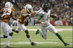 Oregon's Marcus Mariota (8) is chased by Texas' Mykkele Thompson (2) during the first quarter in the Valero Alamo Bowl.