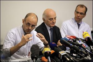 Professor Jean-Francois Payen, left, answers a journalist's question,  as Professor Gerard Saillant, center, and Professor Emmanuel Gay, right, look on, during a press conference at the Grenoble hospital, in the French Alps.