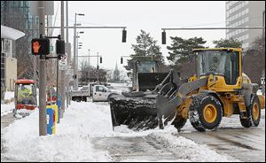 City crews work to remove snow in downtown Toledo near the corner of Superior and Jackson streets in preparation for the next snowstorm, which will be the third one of the season so far.