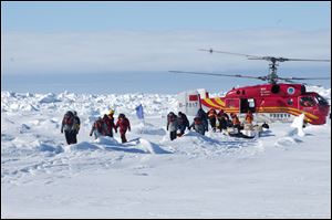 In this image provided by Australasian Antarctic Expedition, passengers trapped for more than a week on the icebound Russian research ship MV Akademik Shokalskiyin are rescued by a Chinese helicopter Thursday, Jan. 2, 2014. 