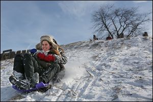 Alyssa Hetrick, left, and her sister Krista, both of Perrysburg, speed down the back side of Fort Meigs during afternoon sledding in Perrysburg under clear skies there Saturday afternoon.