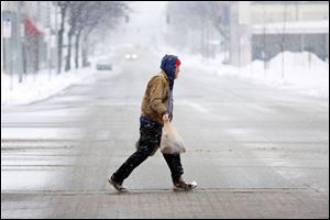 A lone man carries groceries across N. Michigan Street.