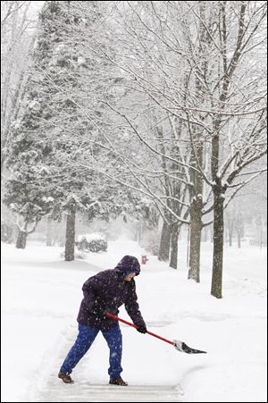 Joan Barrett battles the falling snow as she shovels the walk Sunday in front of her house on Middlesex near Bancroft Street.