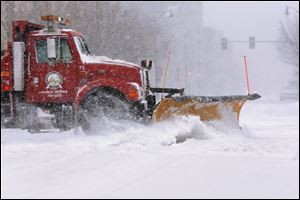 A city snow plow clears a street of snow in an almost deserted downtown as strong winds and snow move through the Midwest, Sunday in Springfield, Ill. 