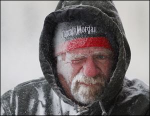 Allan Umscheid, owner of Yards By Al in Lawrence, Kan, feels the bitter wind and catches drifting snow on his face as he runs a snowblower early Sunday morning.