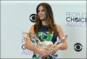 Sandra Bullock, voted the winner of favorite movie actress, favorite dramatic movie actress, and favorite comedic movie actress, holds her awards during the People’s Choice awards ceremony, held Wednesday night in Los Angeles. 
