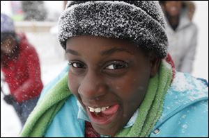 With falling snow on her eyelashes, Latara Walker, 12, laughs while clearing snow Thursday from the driveway of her cousin's home.