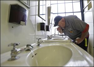 Al Jones of the West Virginia department of General Services tests the water as he flushes the faucet and opens a rest room on the first floor of the State Capitol in Charleston, Va., Monday.