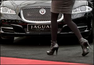 A woman passes by a Jaguar XJ during an Auto Moto Show in Bucharest, Romania. 