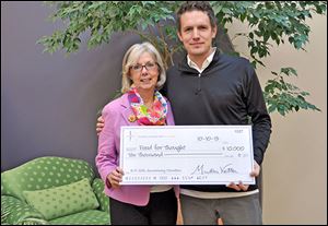 Martha Vetter, chief executive officer and founder of R/P Marketing Public Relations presents Sam Melden, executive director and chief thought officer of Food for Thought with a check. 