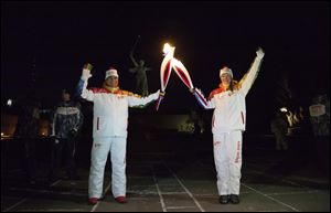 Kamil Larin, left, and Yelena Slesarenko put their torches together during an Olympic torch relay in Volgograd, a city on the Volga River about 500 miles south of Moscow, Russia, Monday with a monument to Motherland at the background. 