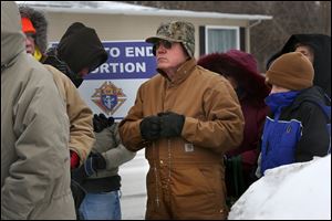 John Stasa of Swanton, center, holds his rosary during a prayer vigil Wednesday outside the Capital Care Clinic, the only remaining Toledo abortion clinic that is fighting the state to keep its license.