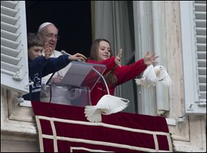 Pope Francis looks at two children as they free doves during the Angelus prayer he celebrated from the window of his studio overlooking St. Peter's Square on Sunday at the Vatican.