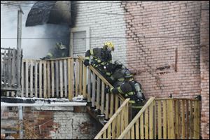 A firefigher is taken down the stairs as smoke pours from the building in North Toledo. Attempts to revive both firefighters were made at the scene.