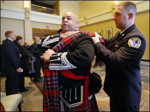 Mike Elston of Virginia Highlands Pipes & Drums gets help with his uniform from Mike Sansone of New City Fire Department in the New York metro area. He is with the Rockland County Firefighters Pipes & Drums.