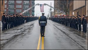 Honor Guard Jeffrey Koenigseker gives commands as firefighters stand at attention during the funeral procession for Toledo firefighter Stephen Machcinski as it passes by Station 5 in downtown Toledo. 