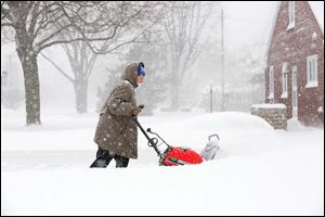 Janice Mossing clears the driveway of her neighbor's home near her home on Lehman.
