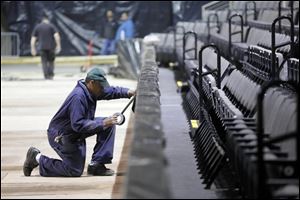 Simmie Vesteda, Jr., puts tape on plastic that is covering the sides of the Huntington Center floor before dirt is spread over it Thursday in preparation for the Professional Bull Riders event this weekend.
