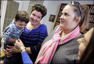 Nicole Yorksmith, left, holds her son,  while standing with her partner Pam Yorksmith. They are among four legally married gay couples who seek to force Ohio to recognize same-sex marriages on birth certificates.