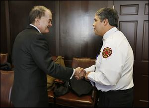 Allan Block, chairman of Block Communications Inc., shakes hands with Toledo fire Chief Luis Santiago after announcing a trust fund has been set up for the children of fallen firefighter James Dickman.