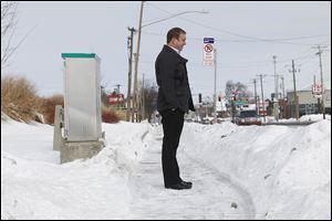 Dennis Kennedy, the city’s  senior management of code enforcement, stands on a shoveled walk in front of Elder-Beerman on Secor.  The city has ‘a spotty history of enforcement’ of the ordinance that requires clearing walks of snow after a storm. 