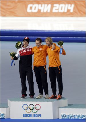 Silver medallist Canada's Denny Morrison, left, gold medallist Stefan Groothuis of the Netherlands, center, and bronze medallist Michel Mulder of the Netherlands, celebrate during the flower ceremony for men's 1000-meter speedskating.