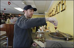 Maumee Valley Chocolate and Candy co-owner Jason Peters dips strawberries into melted chocolate in his shop.