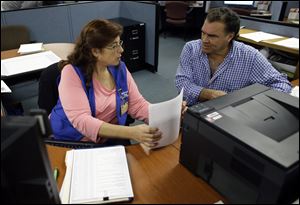 Rose Capote-Marcus, left, helps Waldemar Vega, 50, with problems he is having receiving his unemployment benefits at WorkForce One, in Davie, Fla. on Feb. 6.