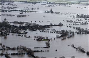 Flood waters inundate the area as one home stands alone and dry near the flooded village of Moorland in Somerset, southwest England, Thursday.